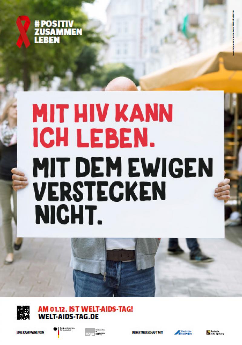 Welt-Aids-Tag 2016, Person verdeckt mit Schild ihr Gesicht. Auf dem Schild steht "Mit HIV kann ich leben. Mit dem ewigen Verstecken nicht."