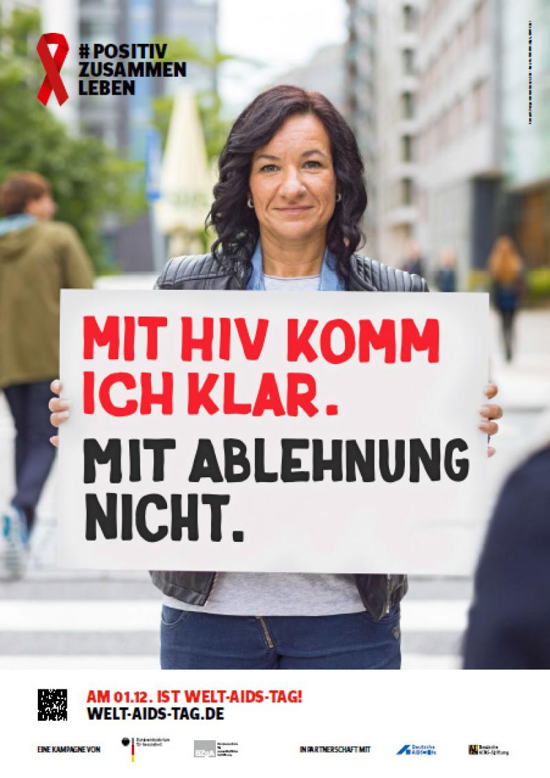 Welt-Aids-Tag 2016, Frau hält Schild hoch mit dem Spruch "Mit HIV komm ich klar. Mit Ablehnung nicht."