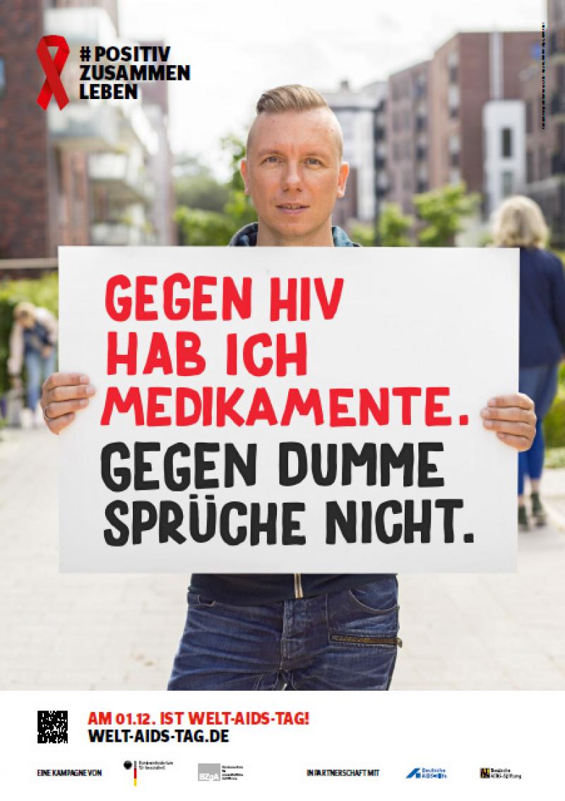 Welt-Aids-Tag 2016, Mann hält Schild hoch mit dem Spruch "Gegen HIV habe ich Medikamente. Gegen dumme Sprüche nicht.