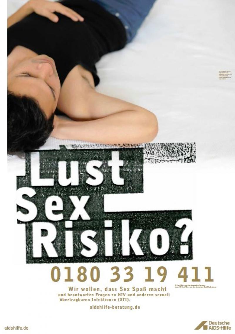 Mann in schwarzem T-Shirt und Jeans auf weißem Bettlaken. Aufschrift "Lust, Sex, Risiko?" Mit Rufnummer für Telefonberatung.