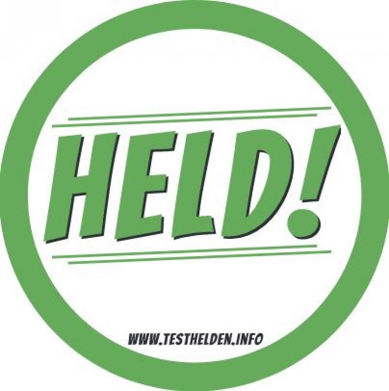 Aufkleber aus der Kampagne "Testhelden". Grüne Umrandung, in der Mitte der Spruch "Held!"