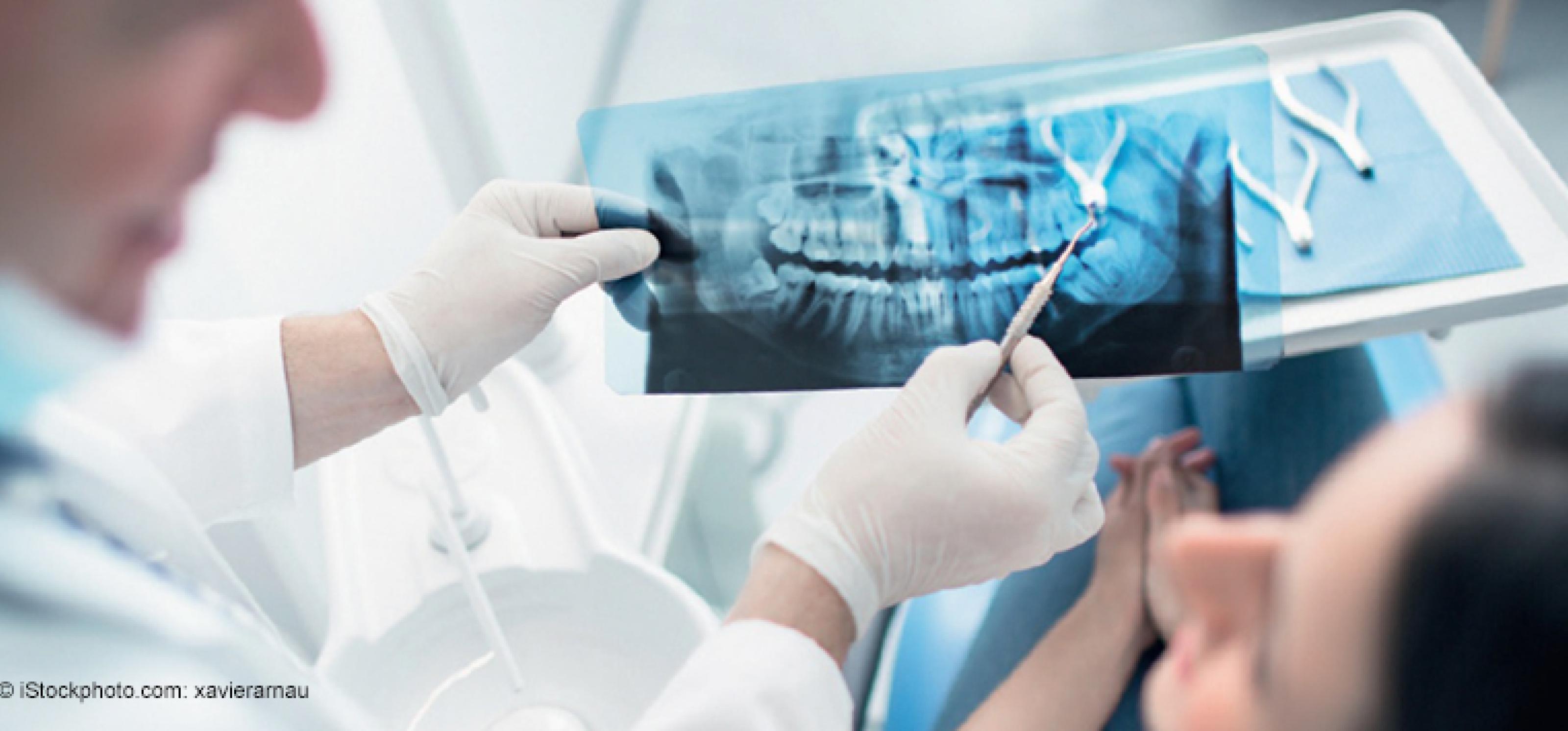 Zahnarzt zeigt im Gespräch mit Patientin ein Röntgenbild