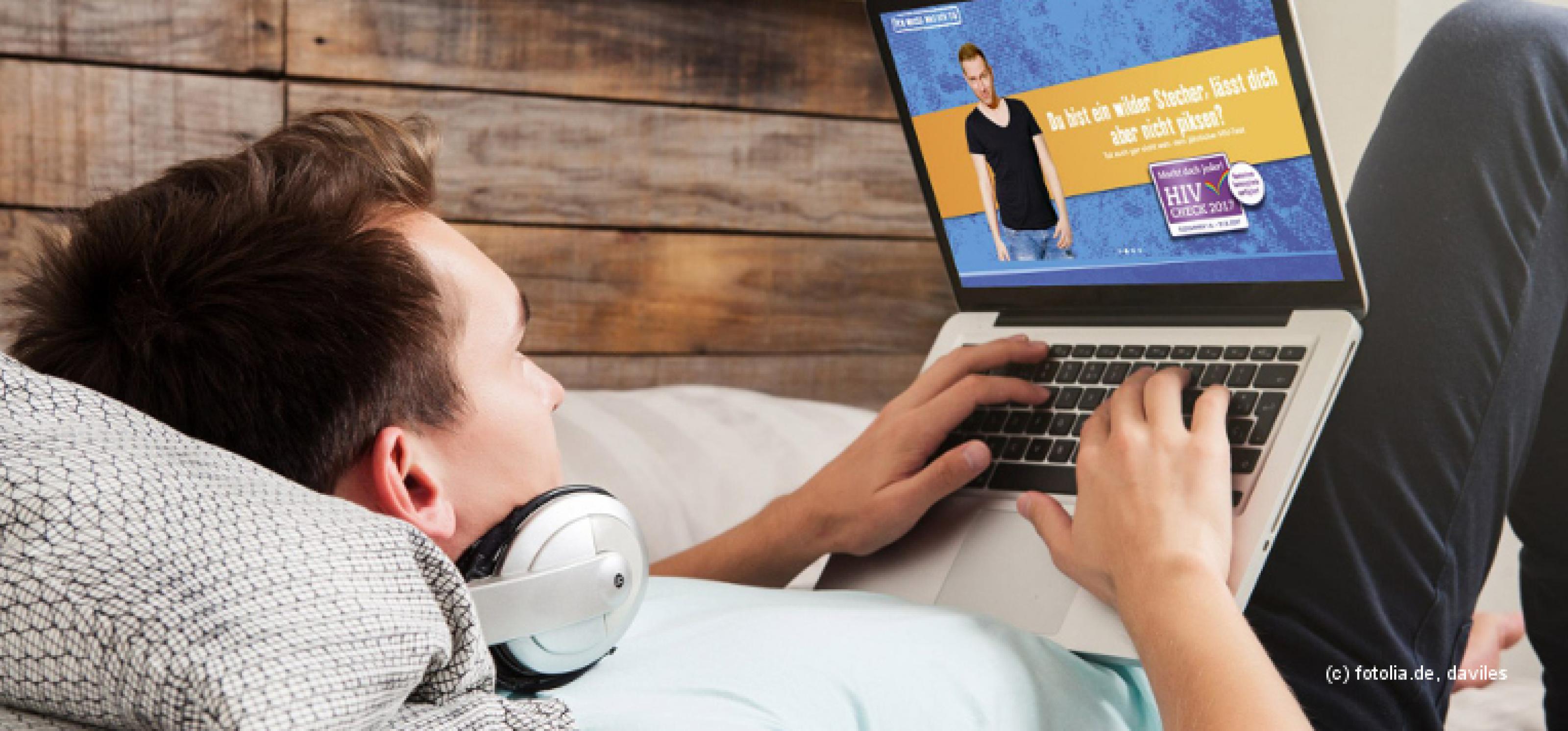 Junger Mann mit Kopfhörern liegt auf einem Bett und surft mit einem Laptop im Internet. Auf dem Laptop-Bildschirm ist die Website www.macht-doch-jeder.de zu sehen.