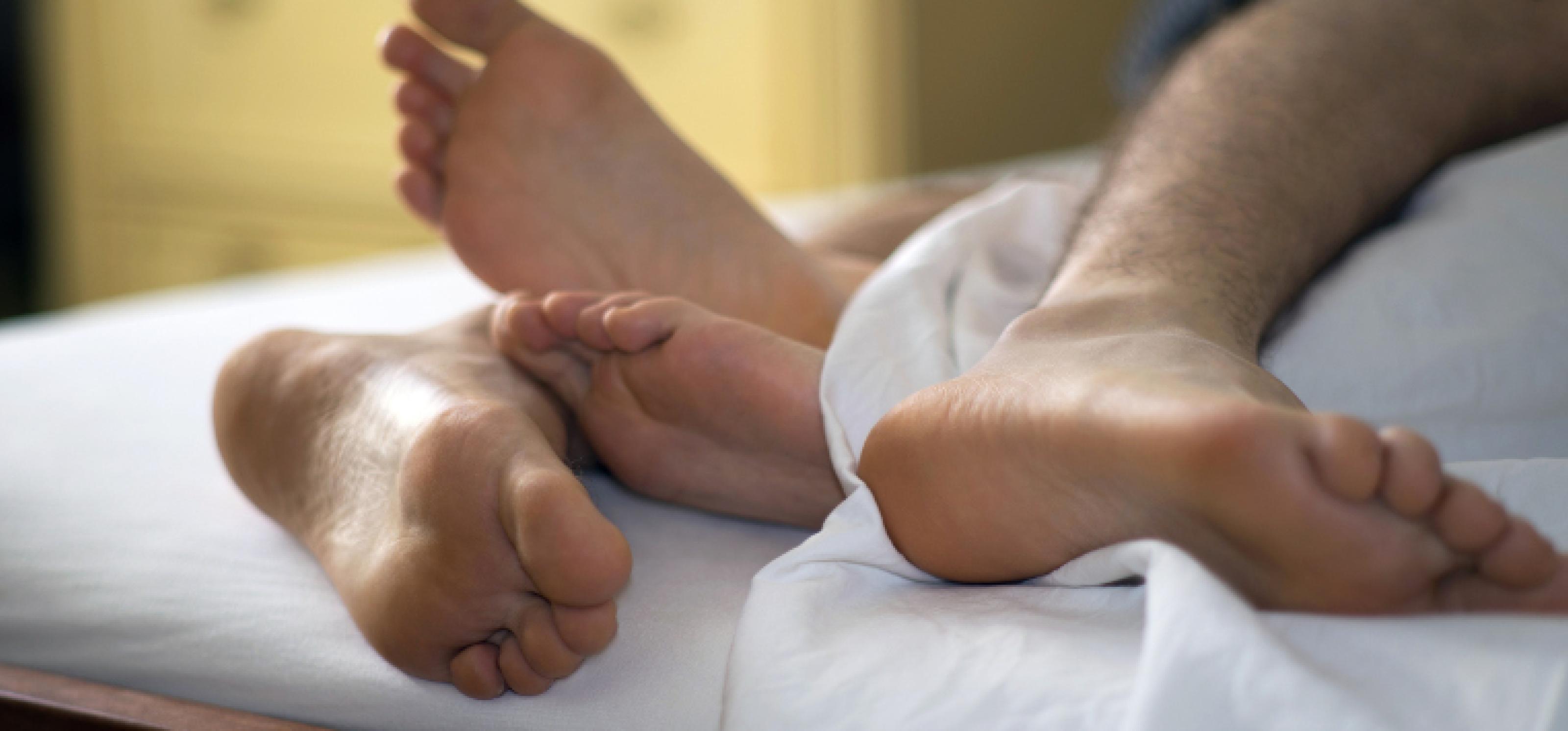 Zwei Paar Füße ragen unter einem Bettlaken hervor